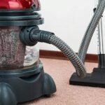 Close-up of a modern vacuum cleaner with water filtration on carpet floor indoors.